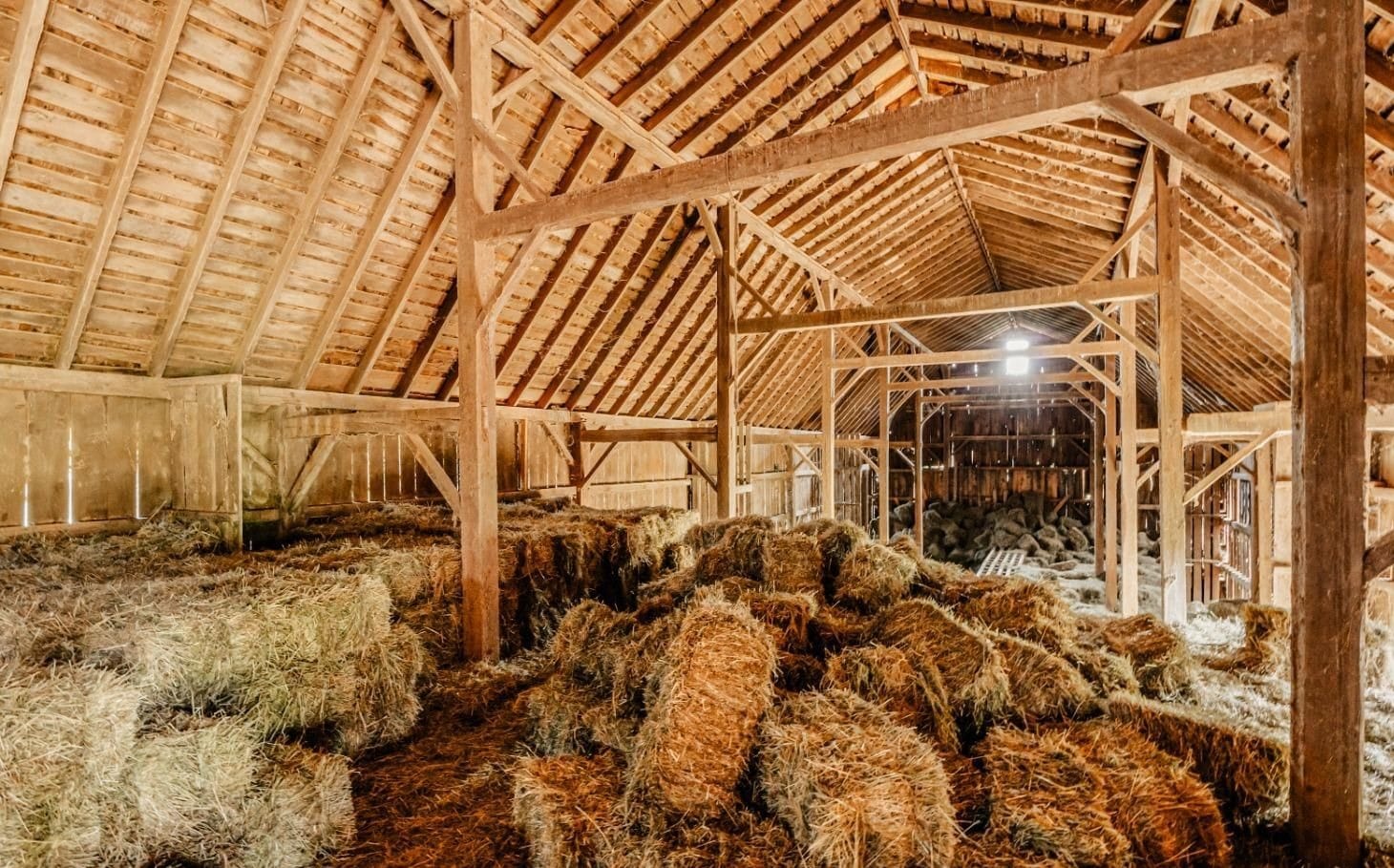 Ashridge red barn hayloft — post-and-beam interior with stacked hay bales, South Kortright, New York