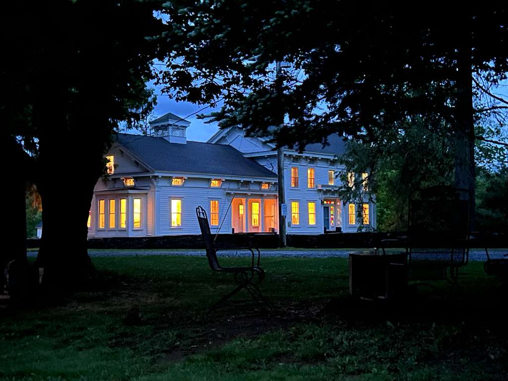 Greek Revival farmhouse at Ashridge Estate at dusk — period interiors, stone fireplace, stained-glass transom windows