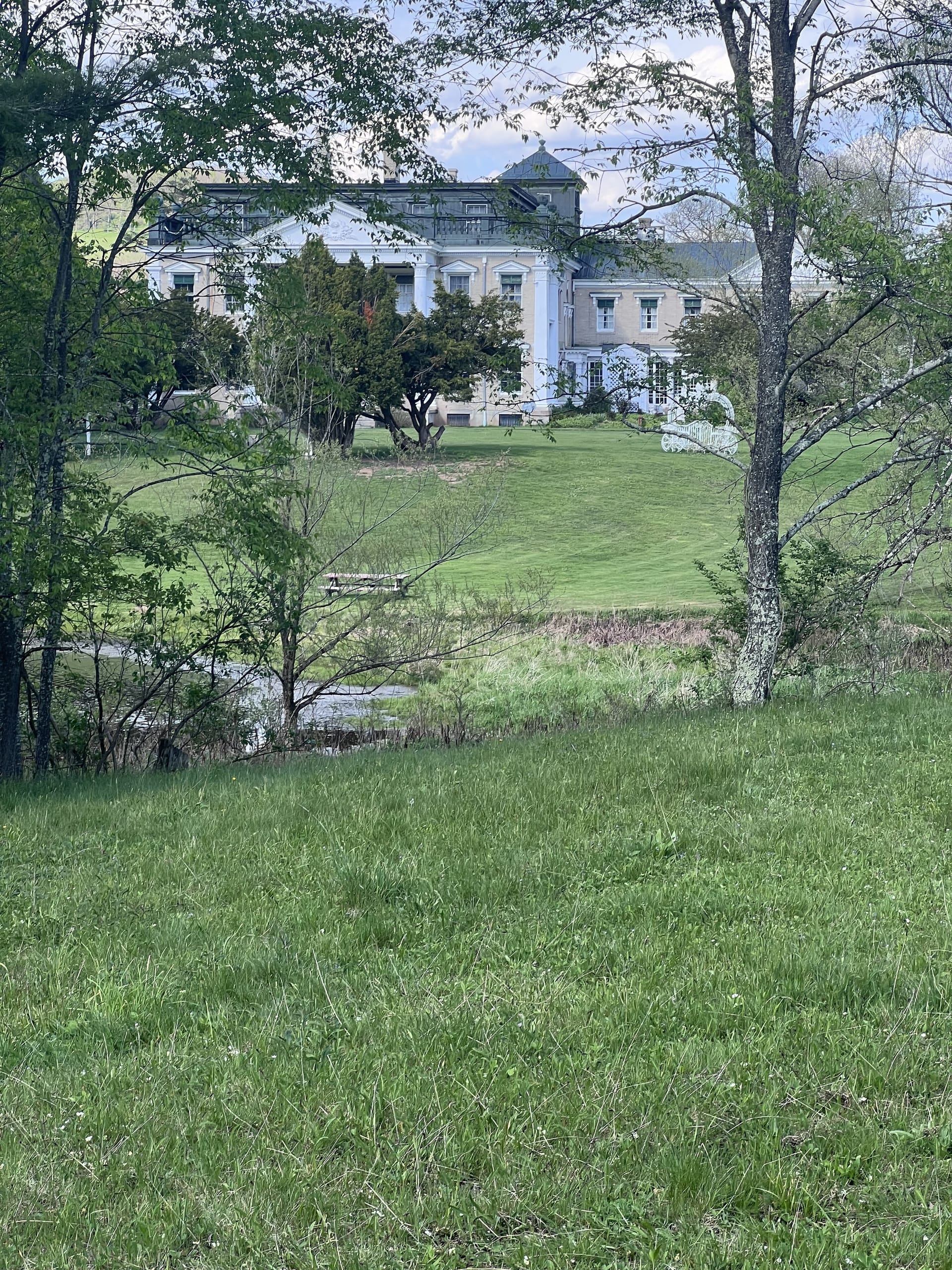 Ashridge mansion seen through trees across a stream — historic estate campus, South Kortright, New York