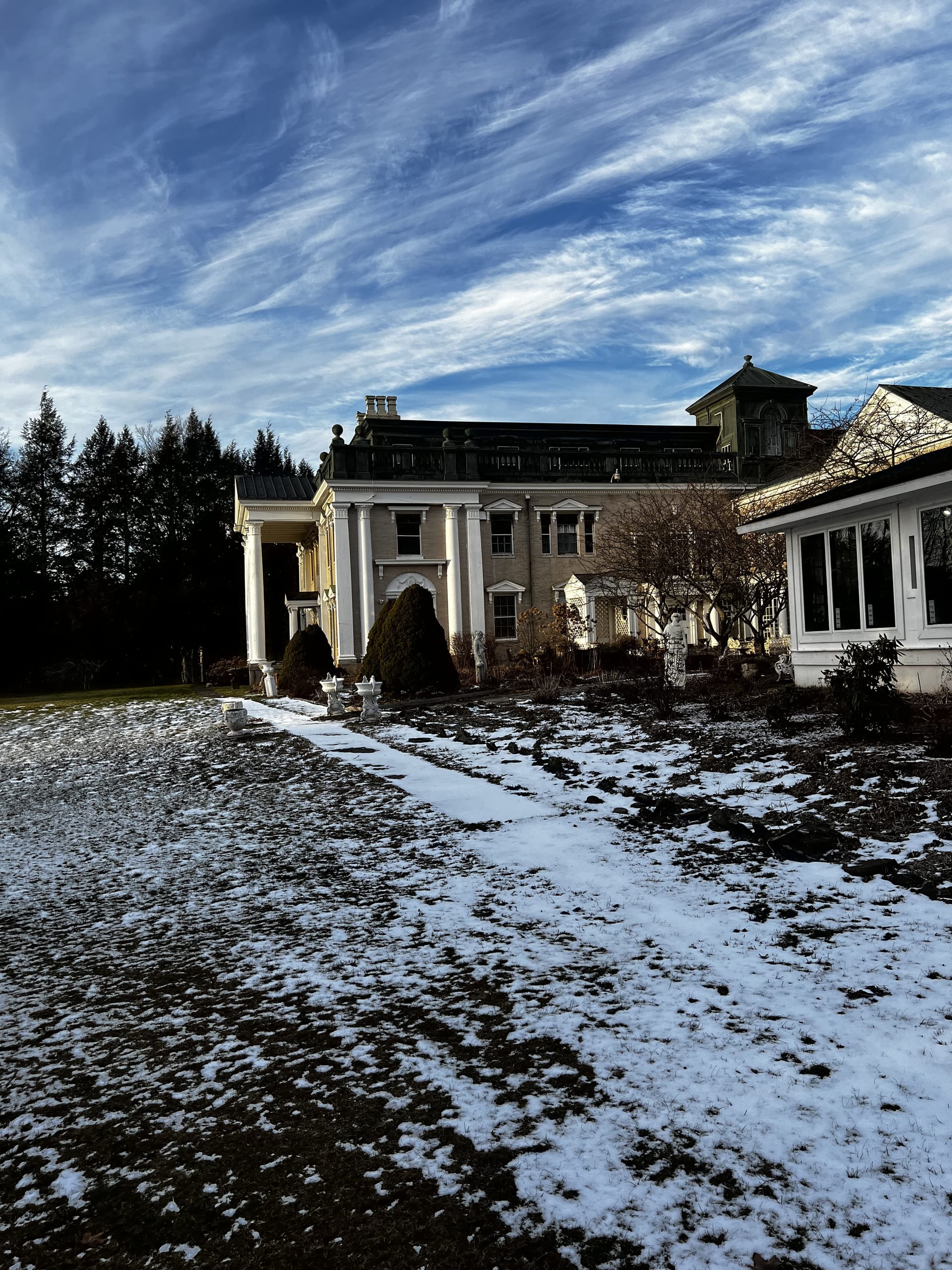 Ashridge mansion in winter — side view with the sunroom wing, original copper roof, and dramatic winter sky