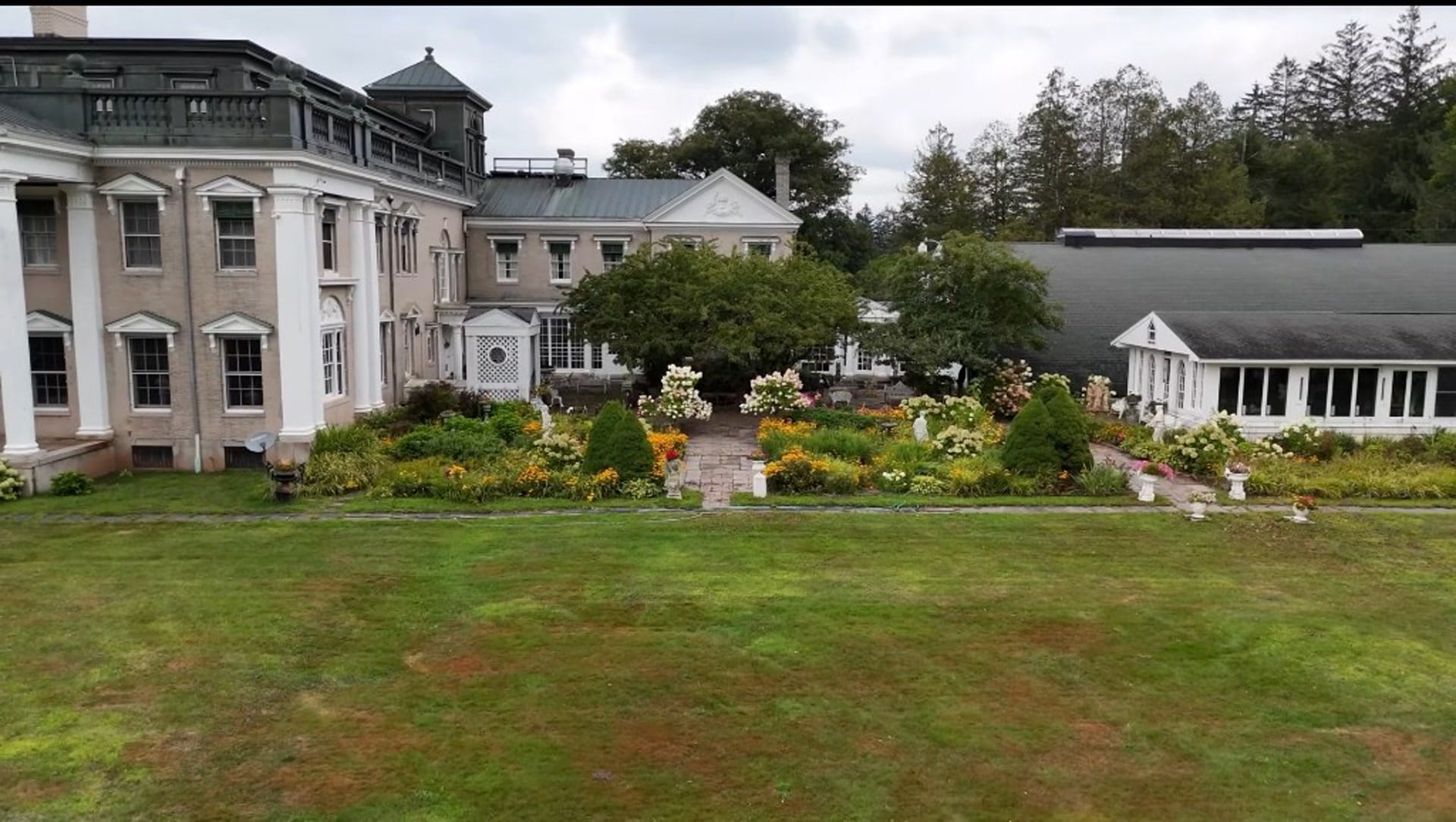 Ashridge mansion and formal flower garden — stone paths, hydrangeas, and conservatory wing from the terrace lawn, South Kortright, New York