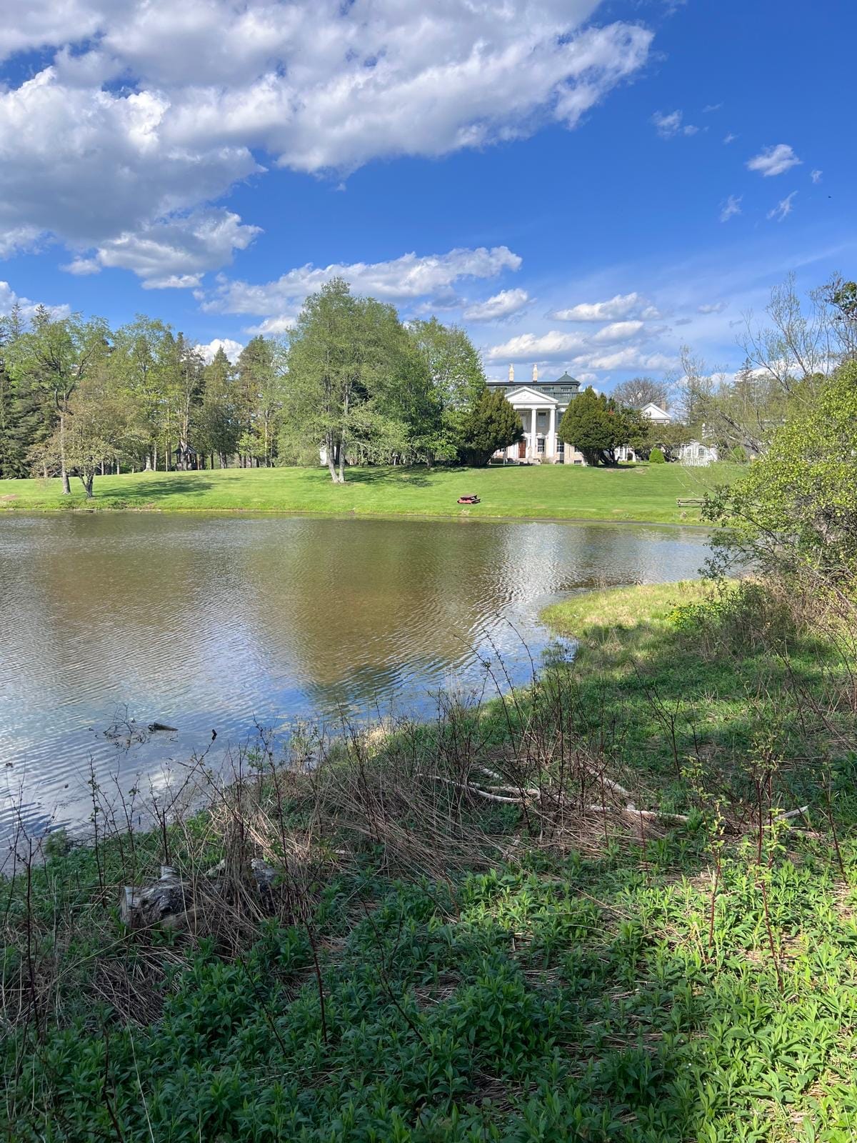 Ashridge mansion from the lake shore — Georgian manor above open lawn and pond, Catskills, New York