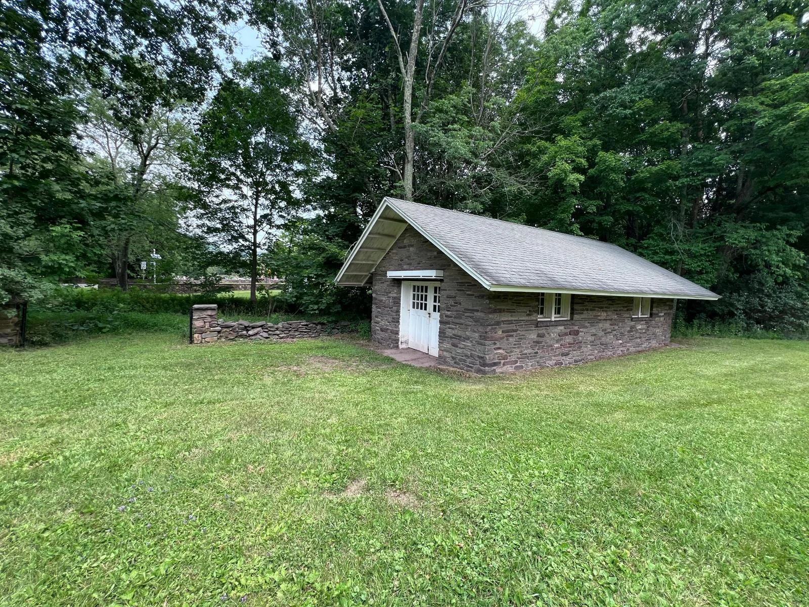 The original stone house — coursed stone walls and white multi-pane carriage doors.